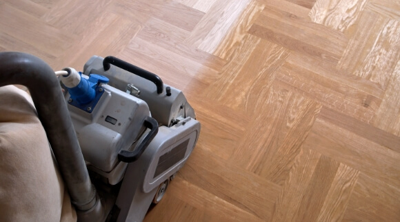 Floor sander refinishing parquet hardwood floor with dustless sanding machine